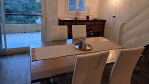 A dining area with a table, chairs, a view of the outdoors, a window, and a staircase. - Apartment 'Porticcio Terra Bella 1' with Mountain View, Wi-Fi and Air Conditioning (Grosseto-Prugna)