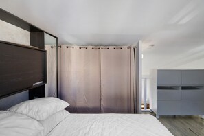 Un dormitorio con cama, armario y cortina.
