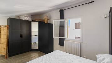 Een slaapkamer met een bed, een kledingkast, een spiegel en een radiator.