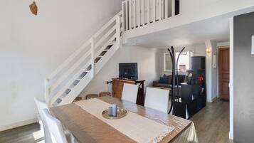 A dining area with a table, chairs, a TV, and a staircase.