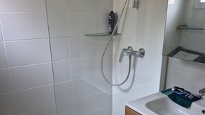 A bathroom with a glass shower enclosure, a white sink with a wooden cabinet, and a mirror above the sink. - Apartment 'Porticcio Terra Bella 1' with Mountain View, Wi-Fi and Air Conditioning (Grosseto-Prugna)