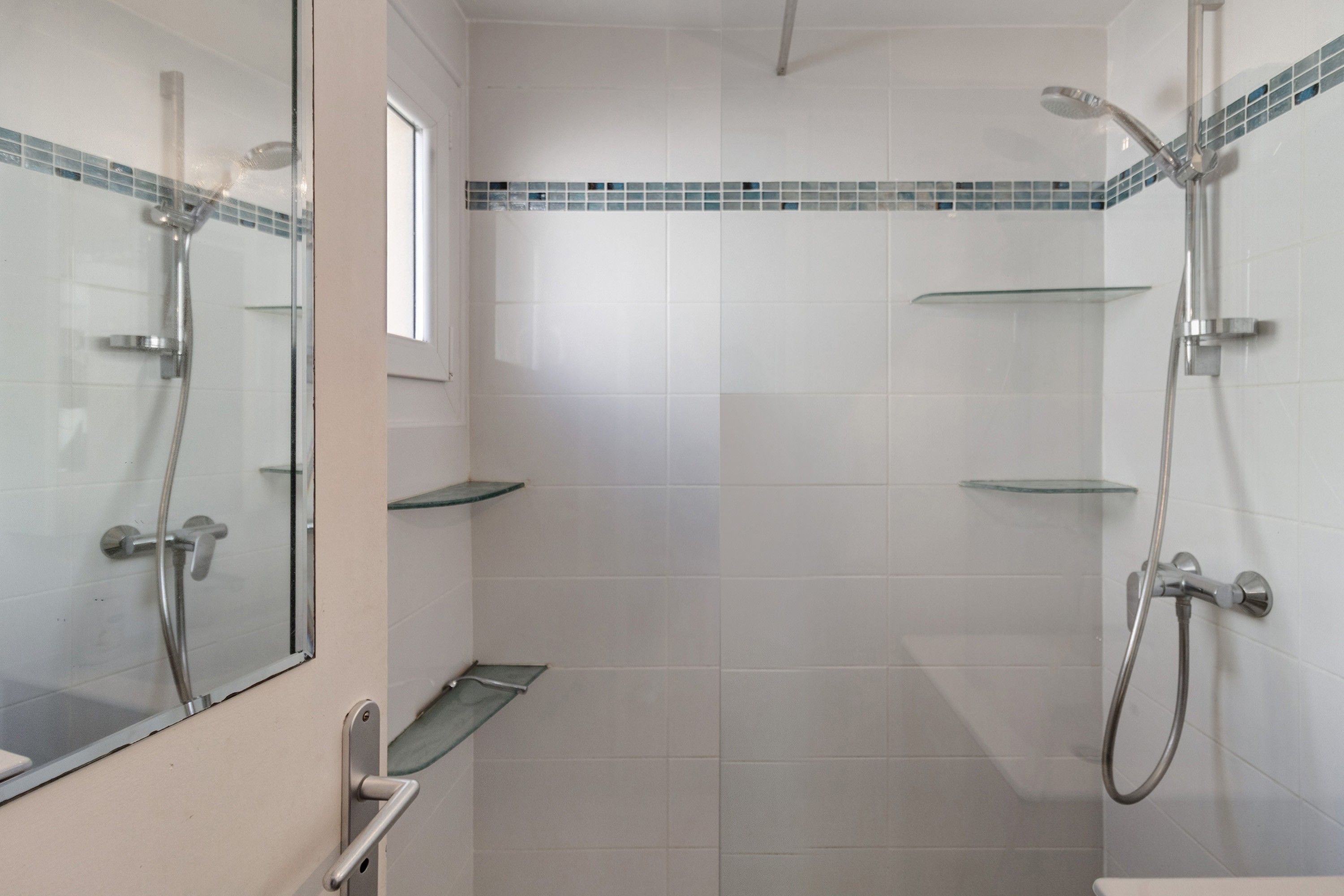 Et badeværelse med glasvægsbruseniche, toilet og håndvask.