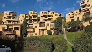 Ett bostadsområde med gula byggnader, en gångstig och grönområden.