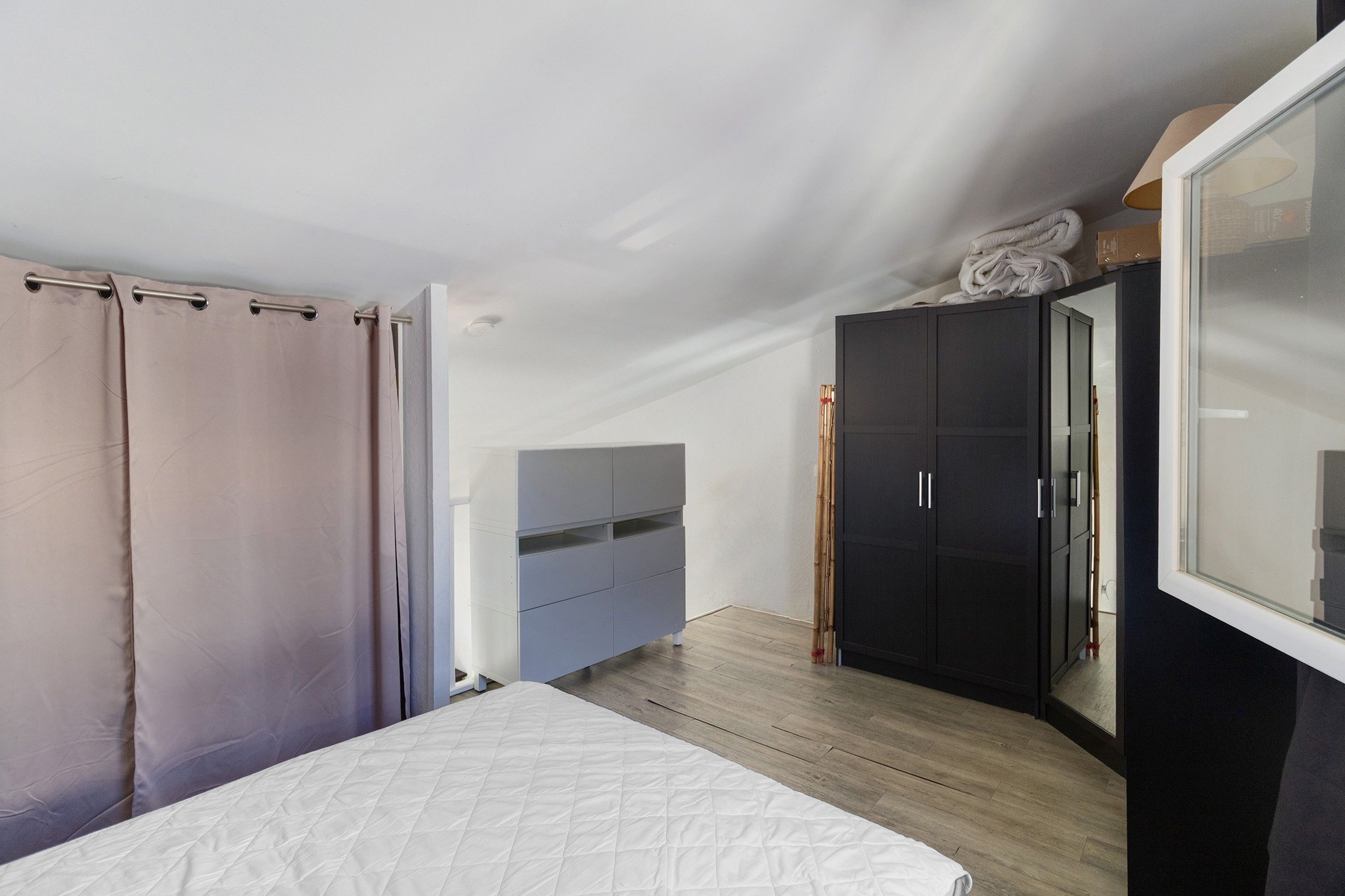 A bedroom with a bed, a wardrobe, and a mirror.