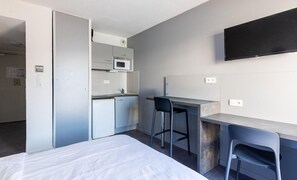 A compact hotel room with a bed, a kitchenette, a desk, and a TV. - À 5km de Montpellier | Piscine sur place | Clim (Saint-Jean-de-Védas)