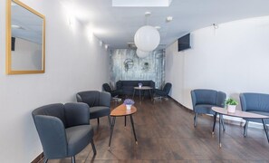 A modern lounge area with sofas and tables, a large mirror, and a textured wall.