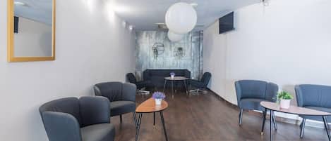 Un área de descanso moderna con sofás, mesas, un espejo grande y una pared con textura.