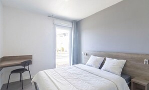 Un dormitorio con una cama, un escritorio y una silla.