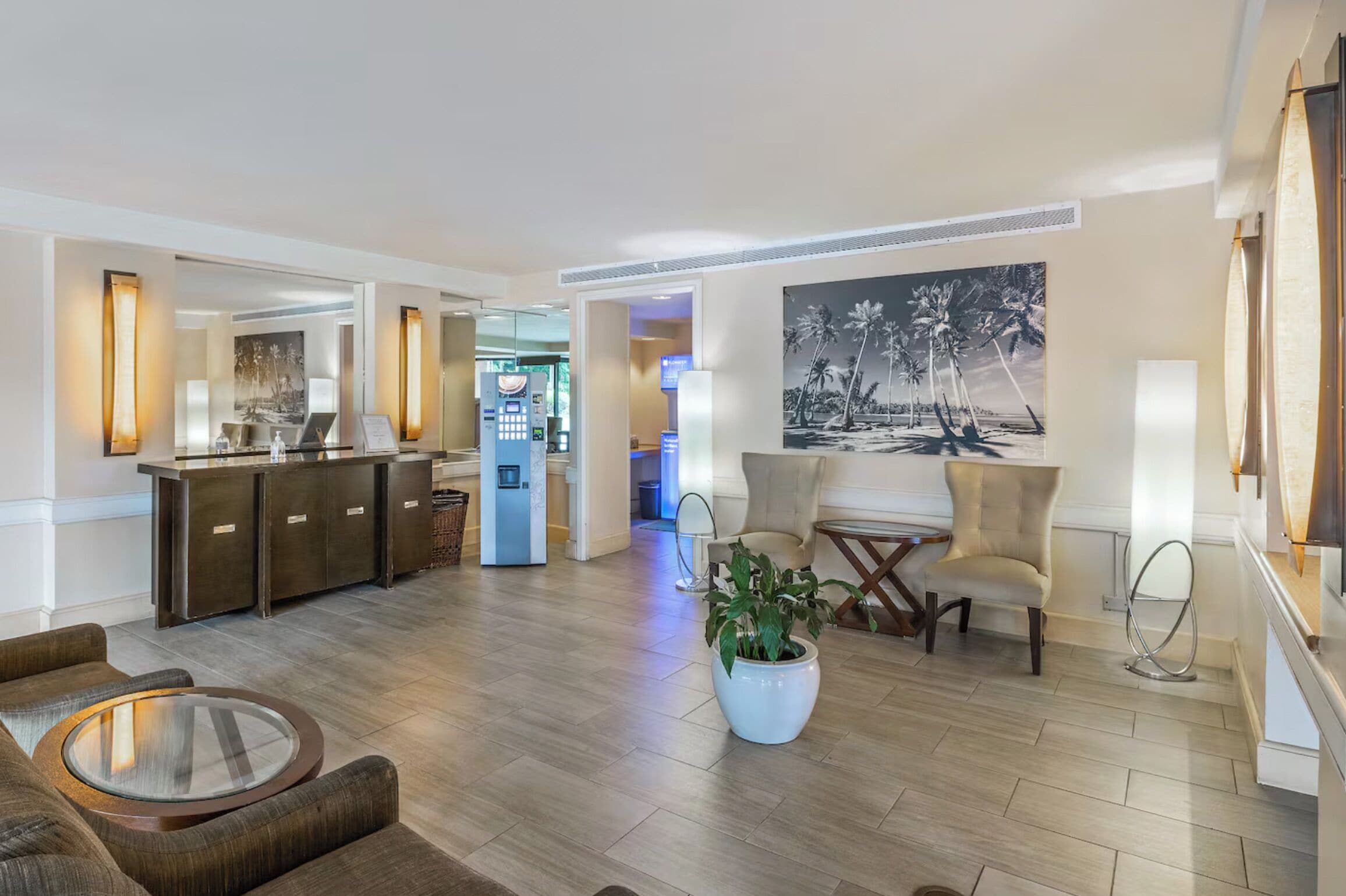A hotel lobby with a reception desk, seating area, and a large painting on the wall.