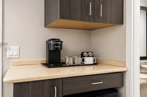 Una kitchenette con una cafetera, un filtro para café y una máquina de café en la encimera.
