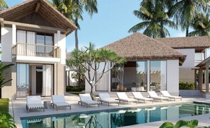 A modern two-story building with a pool, lounge chairs, and palm trees.