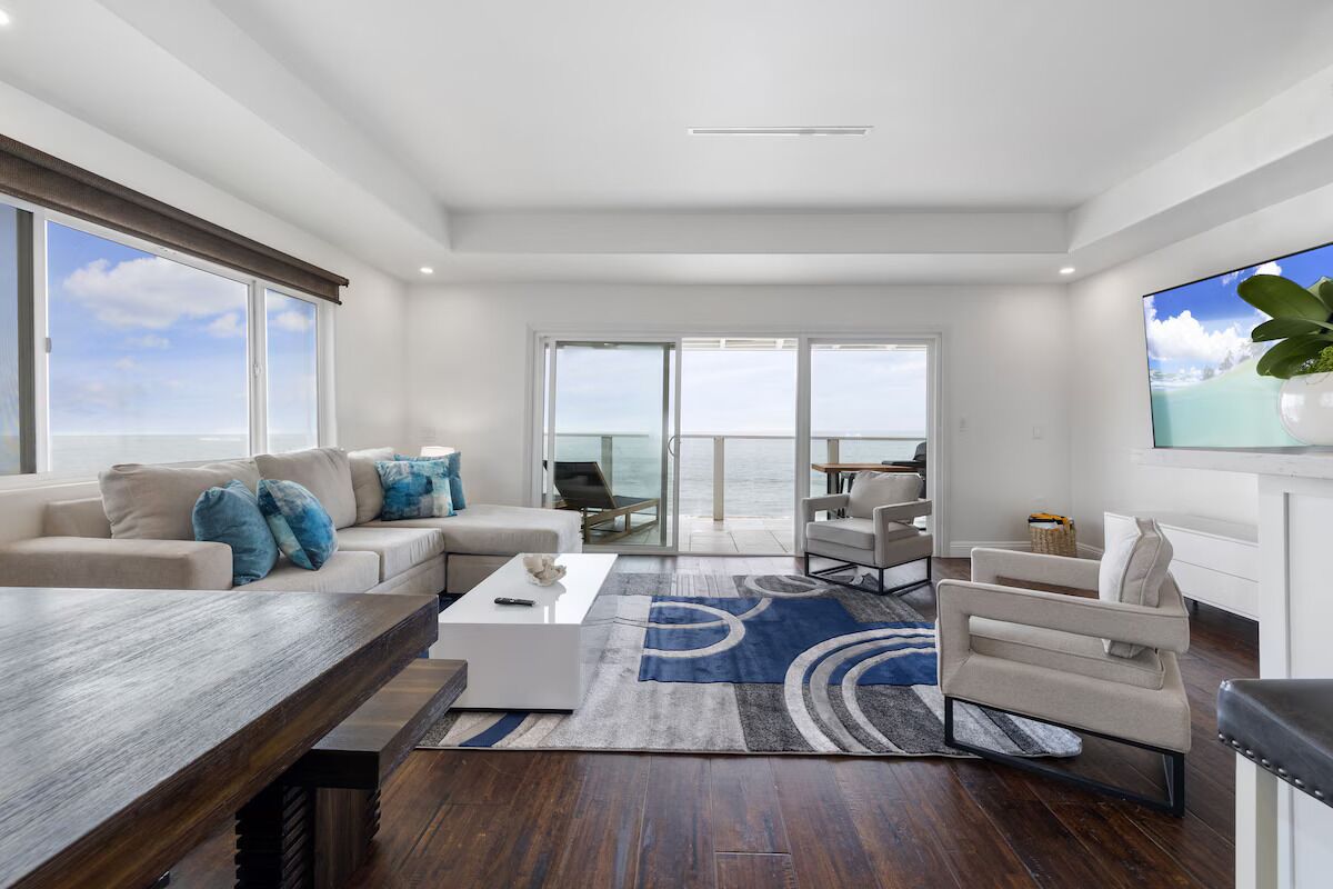 A modern living room with a large window, a sofa, a coffee table, and a TV.