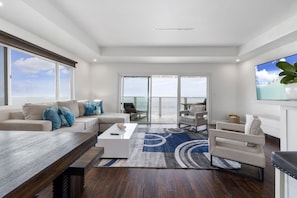 A modern living room with a large window, a sofa, a coffee table, and a TV.