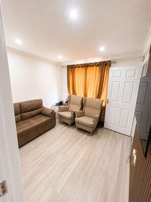 A living room with a sofa, two armchairs, a door, and a curtain. - One Double Bedroom furnished plus living room Self Contain with Shared Kitchen (Orpington)