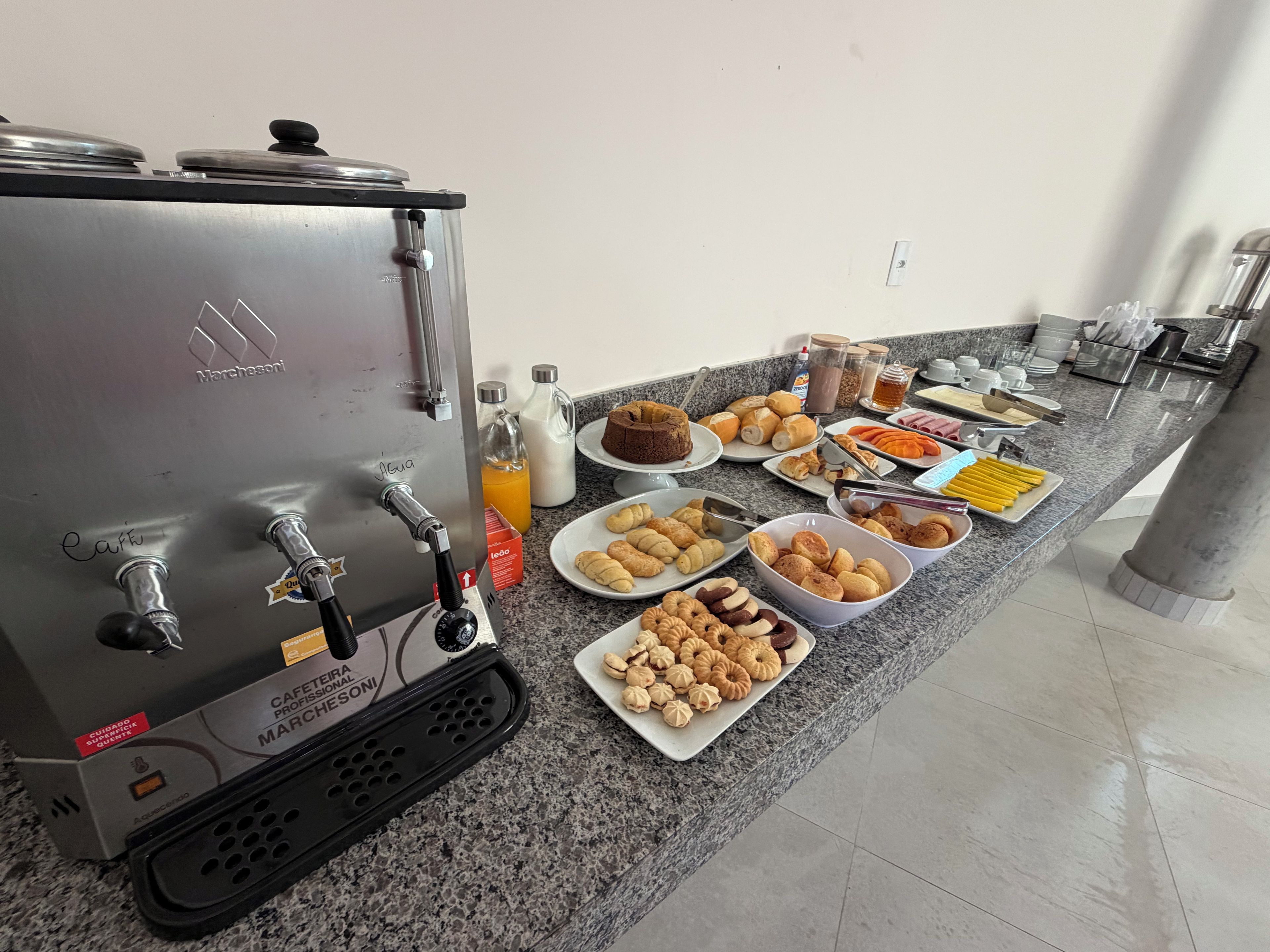 Una kitchenette con una cafetera, diversos alimentos y un bufé de desayuno.