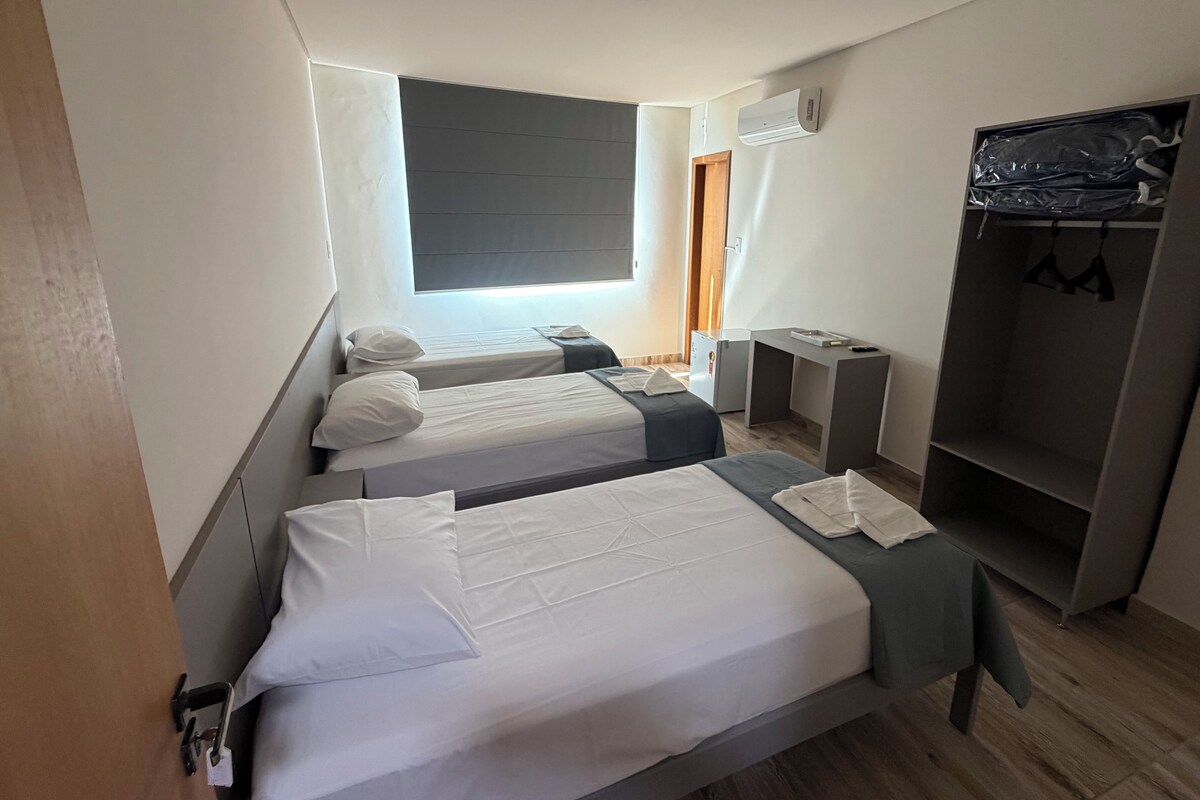 Habitación de hotel con dos camas, un armario, un escritorio y un equipo de aire acondicionado.