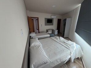 Habitación de hotel con dos camas, un escritorio, un armario y un televisor.