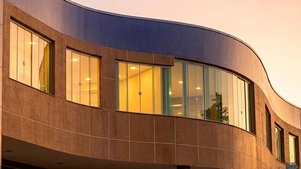 A modern building with curved architecture, large windows, and a tiled facade.