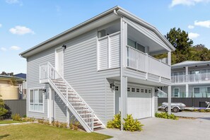 Ein zweistöckiges Wohnhaus mit Veranda, Treppe und Garage.