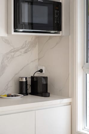 Eine Küche mit einer Mikrowelle, einer Kaffeemaschine und einem Teller mit Speisen.