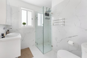 Ein modernes Badezimmer mit Duschkabine aus Glas, einem weißen Waschbecken und einer Toilette.