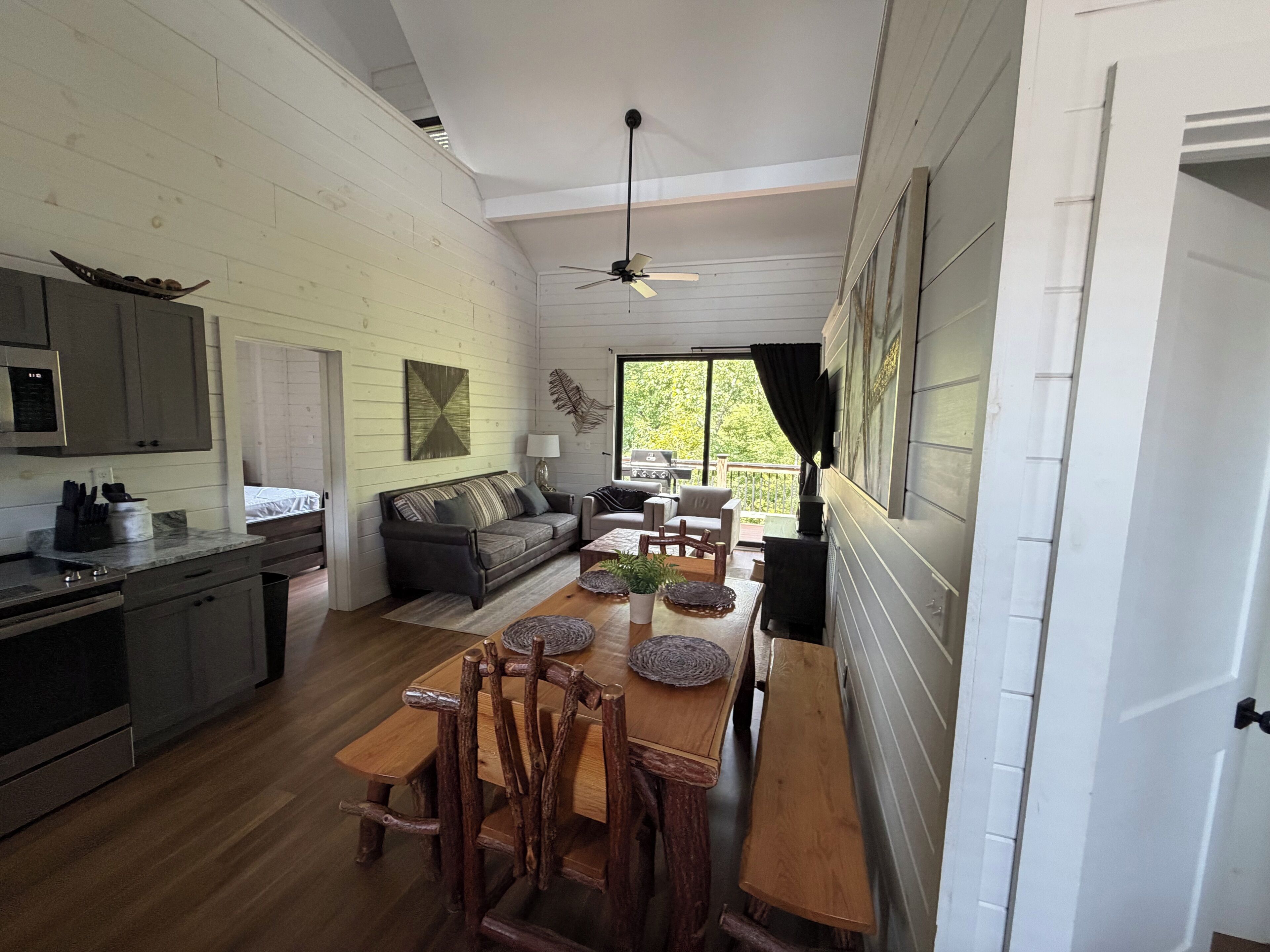 A spacious kitchen with a dining area, wooden furniture, and a ceiling fan.