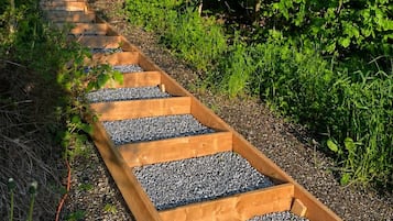 A wooden pathway with gravel steps surrounded by greenery.