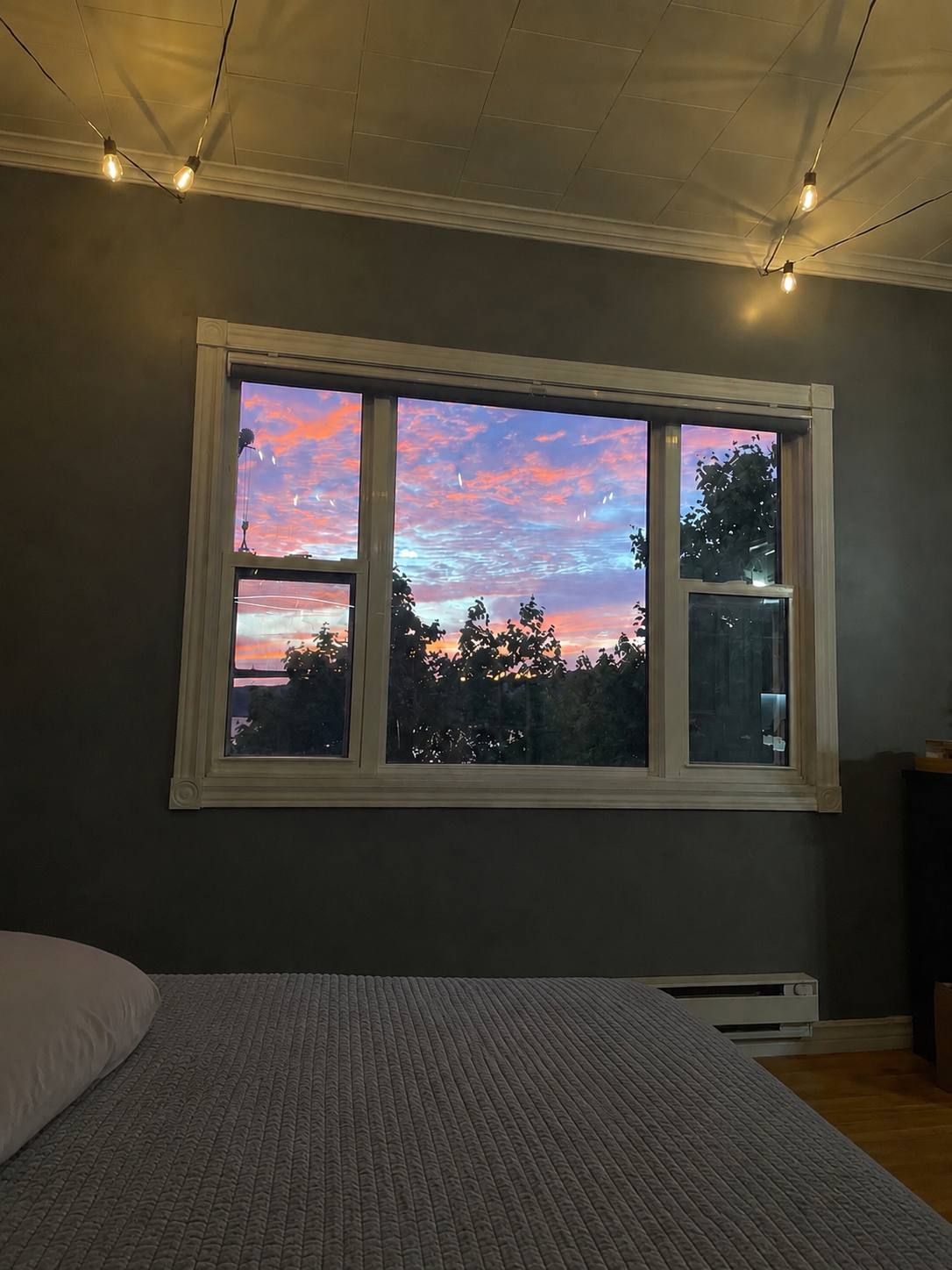 Ein Schlafzimmer mit großem Fenster, einem Bett und einem Heizgerät.