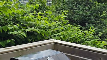 A barbecue grill on a balcony with a view of a cruise ship in the background.