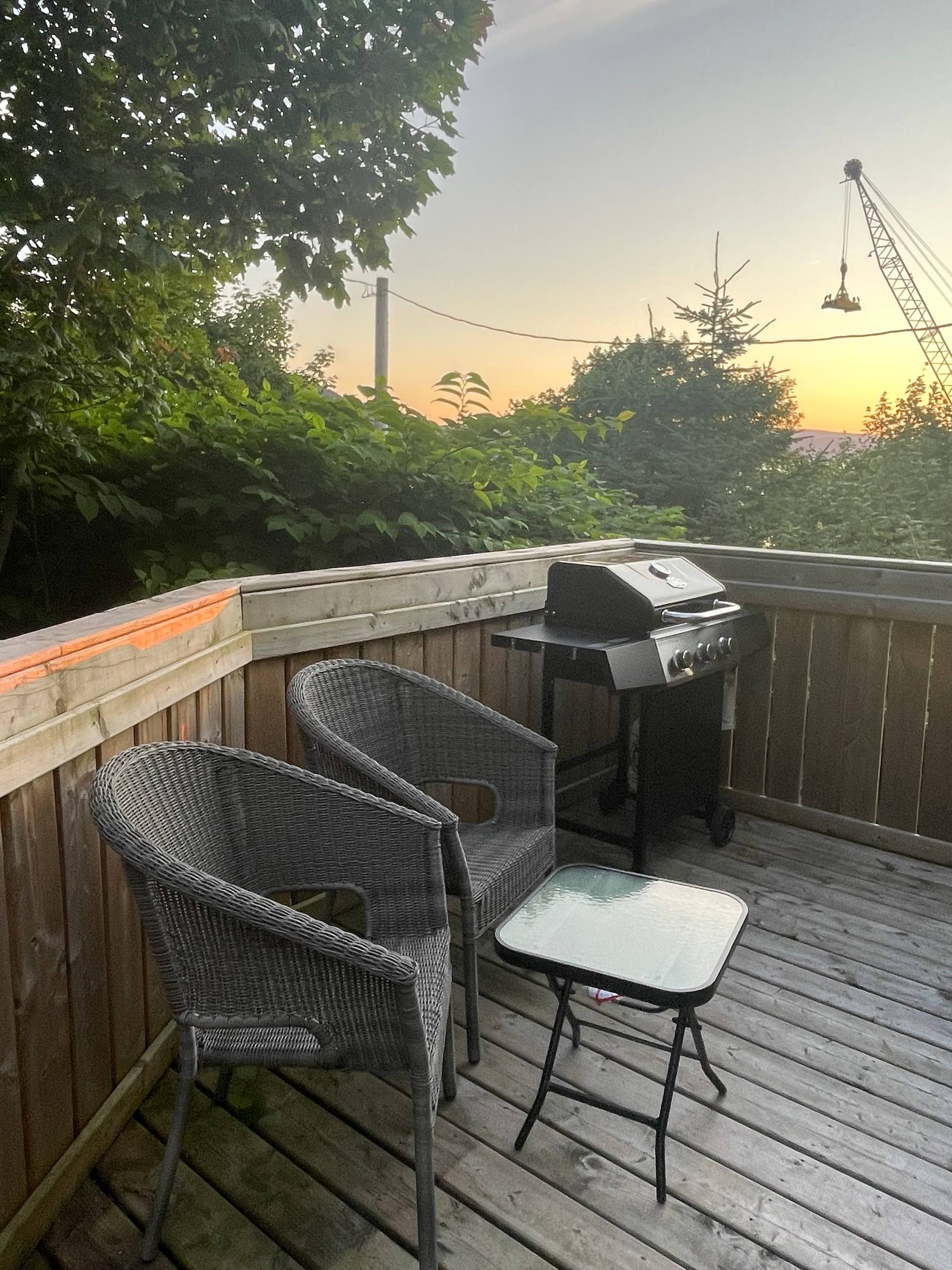 An outdoor deck with wicker chairs, a grill, and a table.