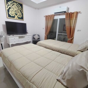 A hotel room with two beds, a TV on a dresser, a fan, and a window with curtains. -  2-bedroom luxurious house with swimming pool. (Tambon San Sai Noi)