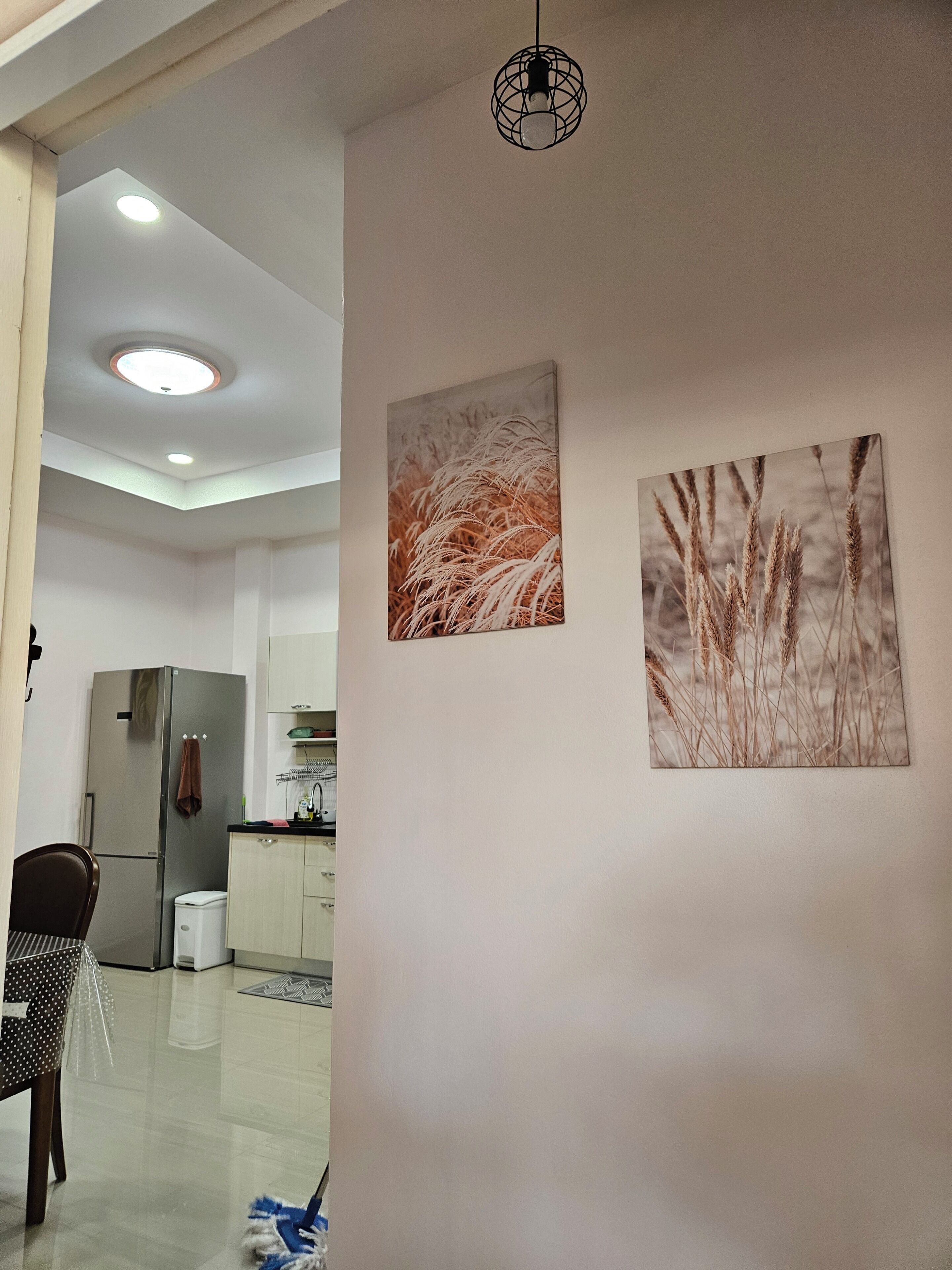 Eine moderne Küche mit Edelstahlgeräten, einem Essbereich mit einem Stuhl und zwei an der Wand befestigten Bildern.