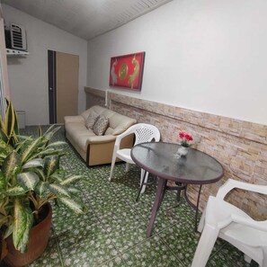 Een compacte, ingerichte kamer met een bank, een tafel en potplanten.