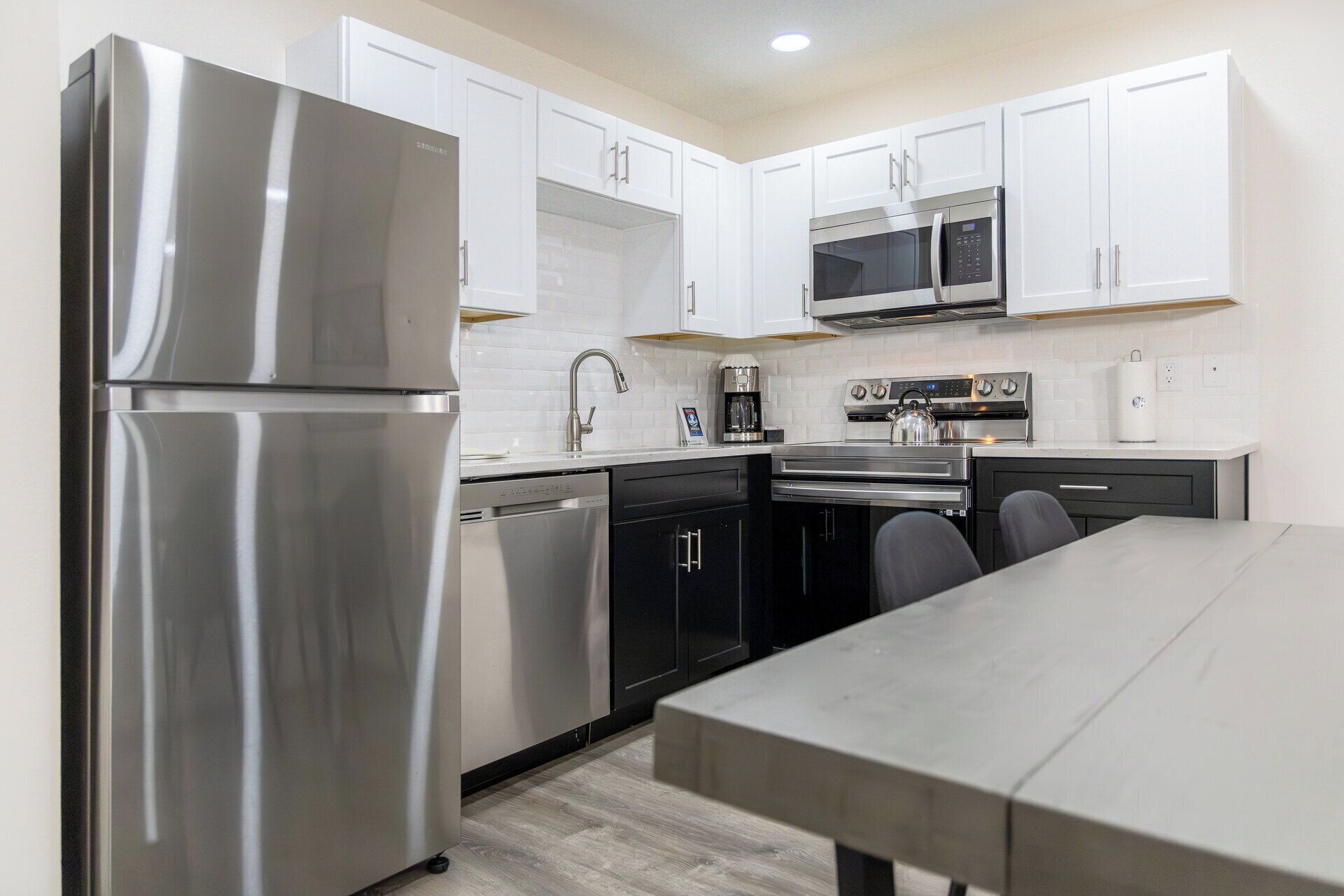 A modern kitchen with stainless steel appliances, white cabinetry, and a dining area with a table.