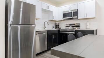 A modern kitchen with stainless steel appliances, white cabinetry, and a dining area with a table.