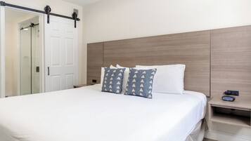 A hotel room with a bed, a nightstand, a wall-mounted heater, and a sliding door leading to a bathroom.