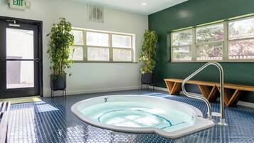 A room with a hot tub, two potted plants, a bench, and a door marked 'EXIT'.
