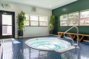 Ein Zimmer mit Whirlpool, zwei Kübelpflanzen, einer Bank und einer Tür mit der Aufschrift 'EXIT'.