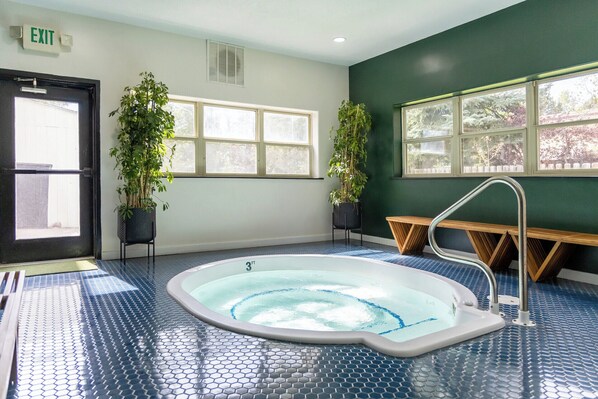 A room with a hot tub, two potted plants, a bench, and a door marked 'EXIT'.