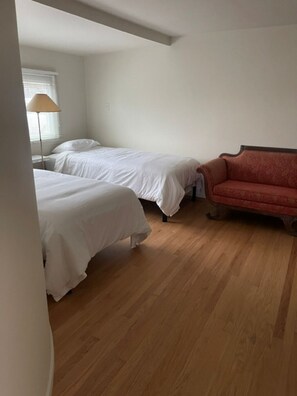 Ein Zimmer mit zwei Betten, einem roten Sofa und einer Lampe.