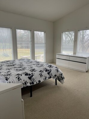 Ein Schlafzimmer mit Bett, Kommode und einem Fenster mit Jalousien.