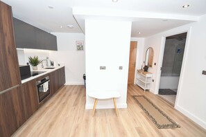 A modern kitchen with dark wood cabinets, a white countertop, and a built-in oven. - Contemporary 2 Bedroom Apartment in Central Leeds (Leeds)