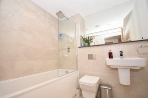 A modern bathroom with a glass-enclosed shower, a white toilet, a pedestal sink, and a trash bin. - Contemporary 2 Bedroom Apartment in Central Leeds (Leeds)