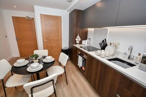 Eine moderne Küche mit Einbauofen, Spüle und Essbereich mit Tisch für vier Personen.
