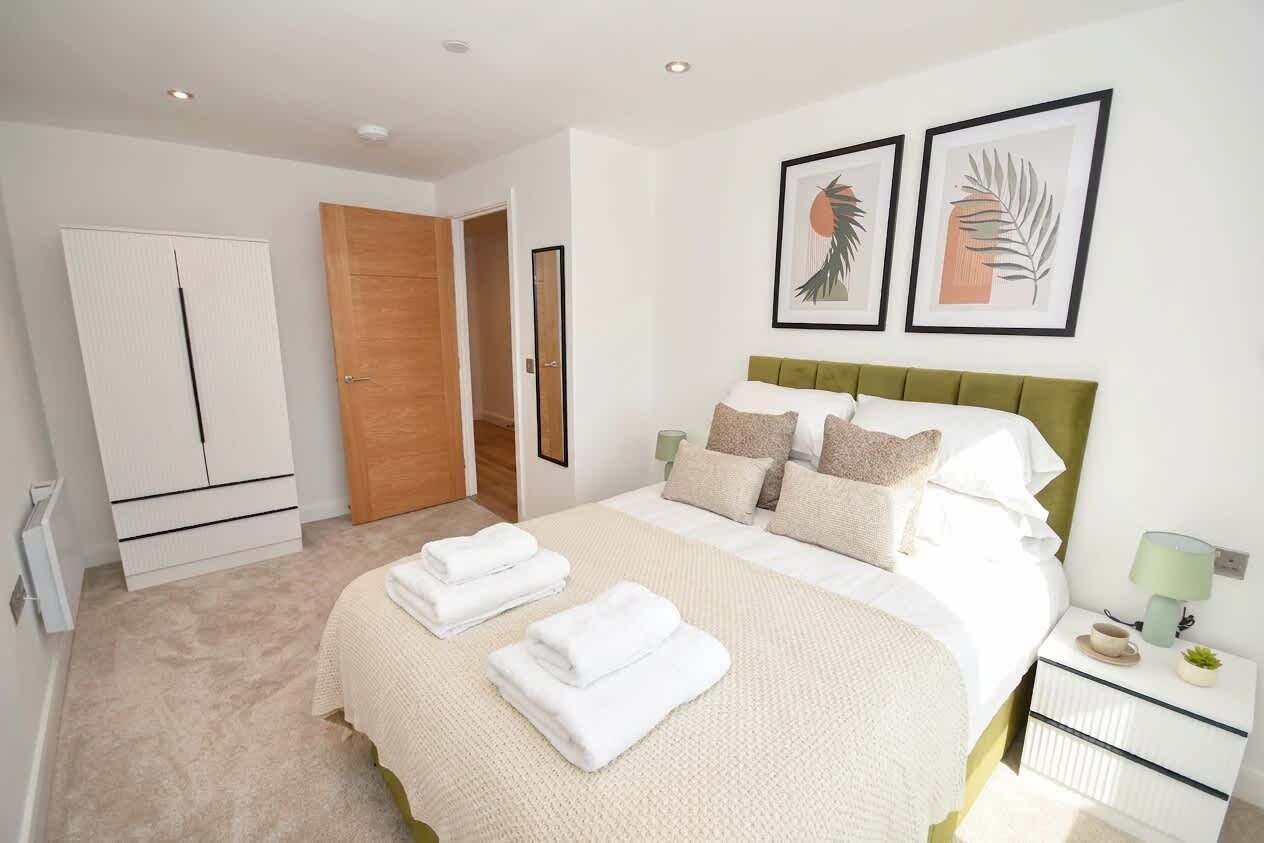 A bedroom with a bed, a wardrobe, a door, and two framed pictures on the wall.