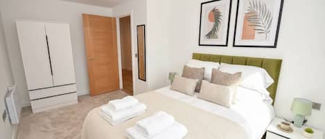 A bedroom with a bed, a wardrobe, a door, and two framed pictures on the wall.