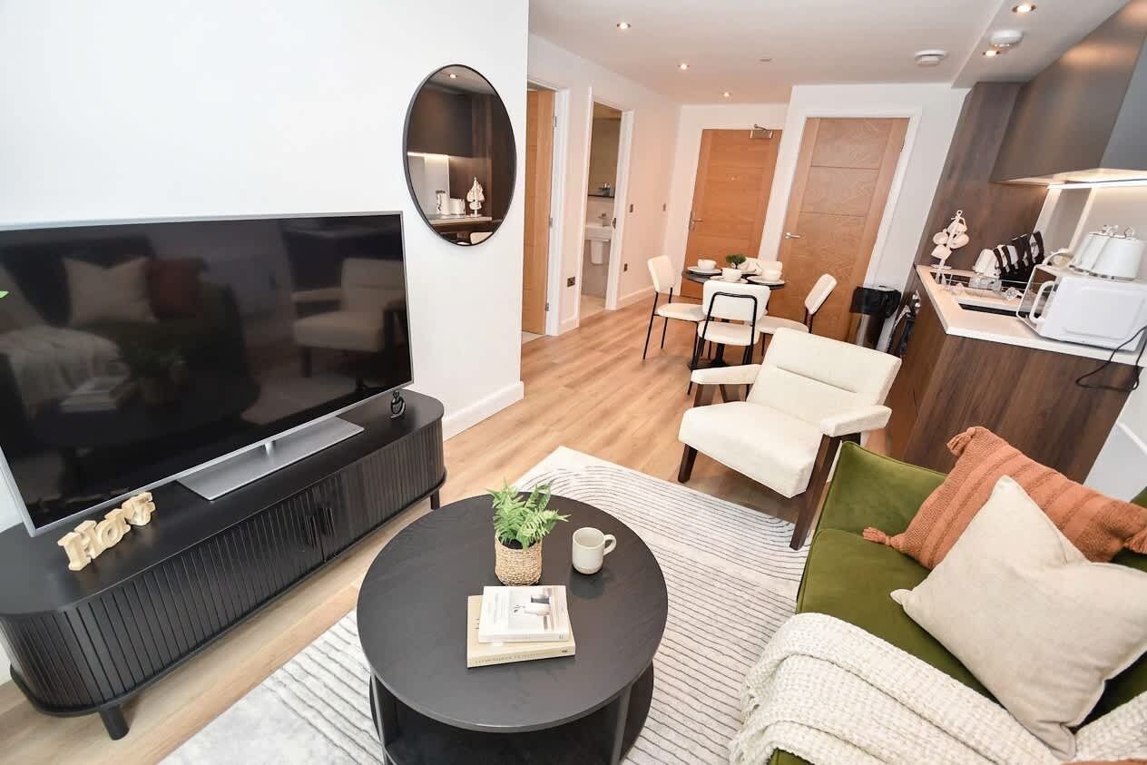 Un salon moderne avec un téléviseur à écran plat, une table basse ronde et un canapé.