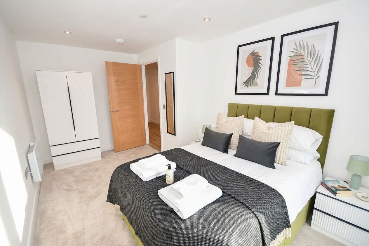 A hotel room with a bed, a wardrobe, a bedside table, and framed artwork on the wall.