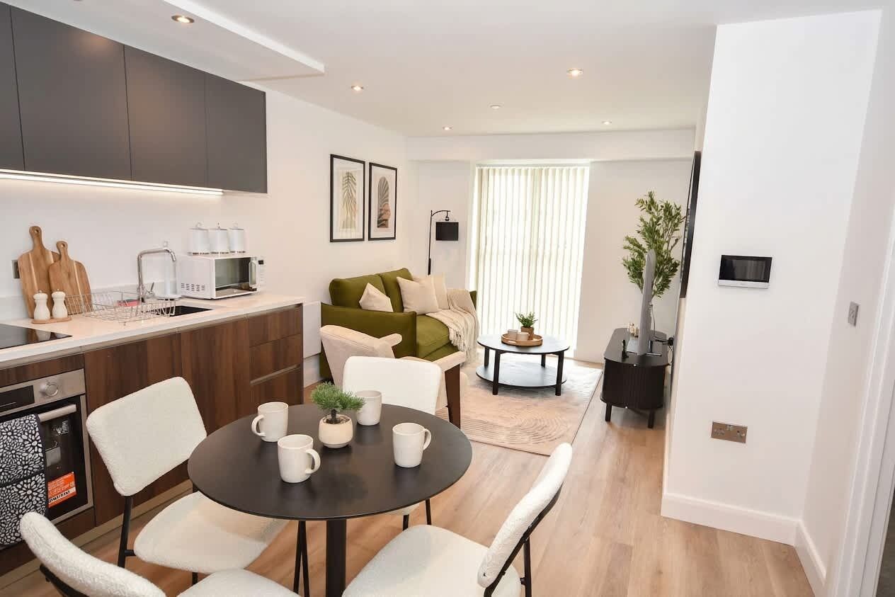 A modern kitchen with a dining area, a sofa, and a small side table.