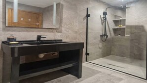 A modern bathroom with a black vanity, a glass shower enclosure, and a wooden cabinet. - Sandra 13 (Marsa)